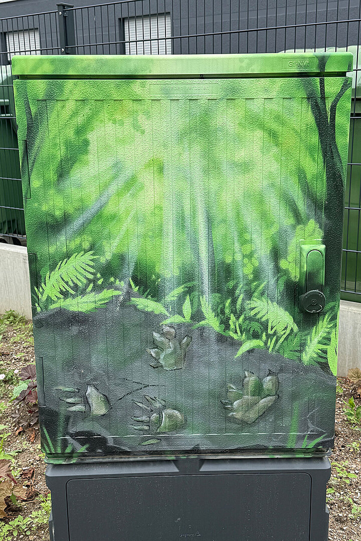 Künstlerisch gestalteter Verteilerkasten in den Erlenhöfen Jena mit grüner Wald- und Pflanzenlandschaft.