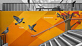 Orangefarbene Fassadenkunst an einer Treppe der Erlenhöfe Jena mit Tauben und einer Goldammer.