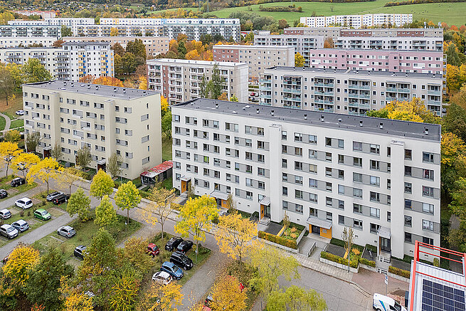 Luftaufnahme eines Wohnquartiers in Jena-Winzerla an der Wanderslebstraße mit modernisierten Mehrfamilienhäusern, Parkplätzen und herbstlicher Begrünung.