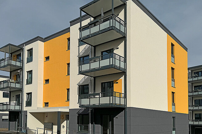 Wohngebäude der Erlenhöfe in Jena-Ost mit großzügigen Balkonen und gelb-weißer Fassadengestaltung.