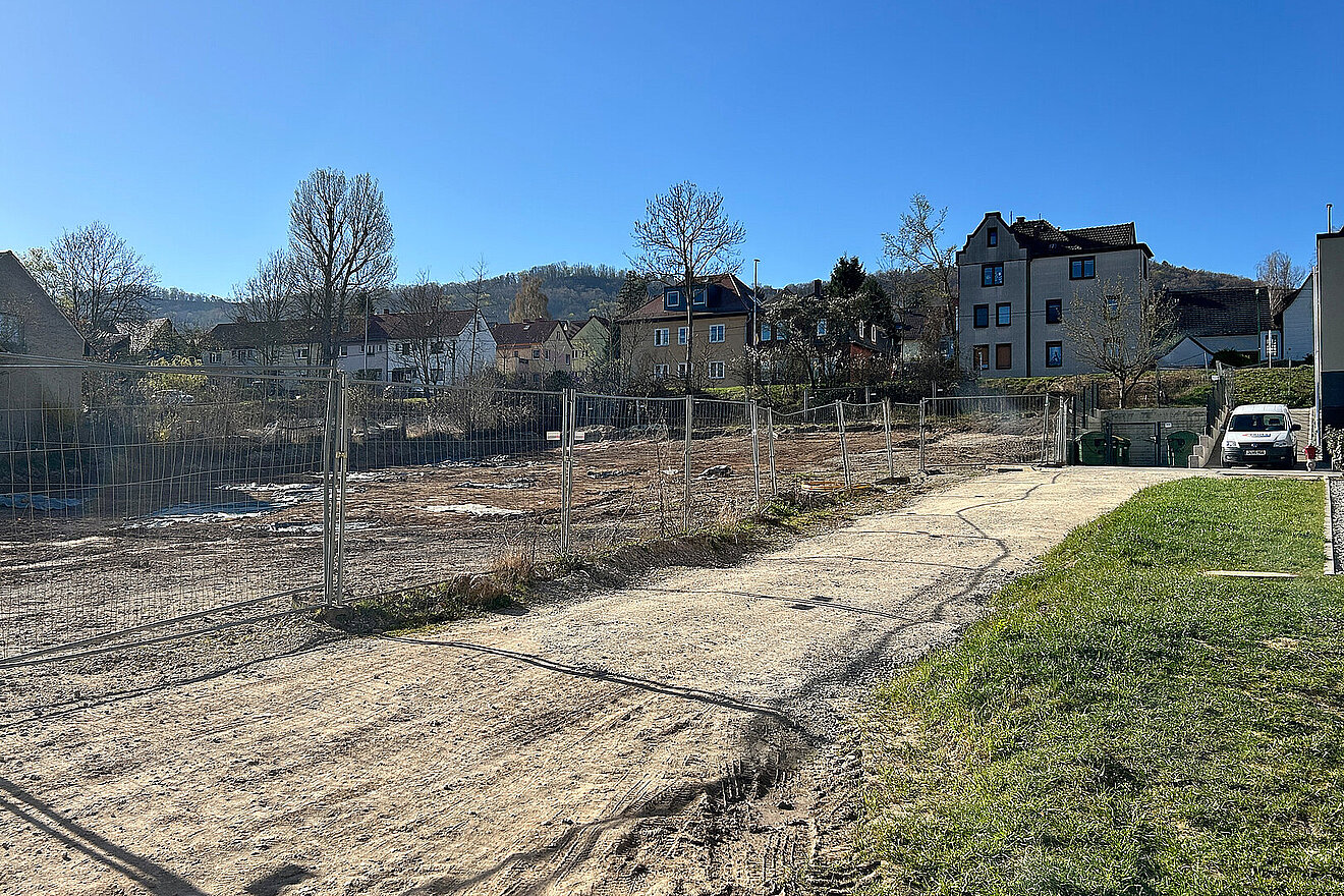 Eingezäuntes Baugrundstück des Wohnprojekts Erlengrün in Jena vor Baubeginn, umgeben von bestehenden Wohnhäusern.