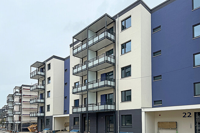 Moderne Wohngebäude der Erlenhöfe in Jena mit großzügigen Balkonen, blau-weißer Fassadengestaltung und laufenden Restarbeiten.