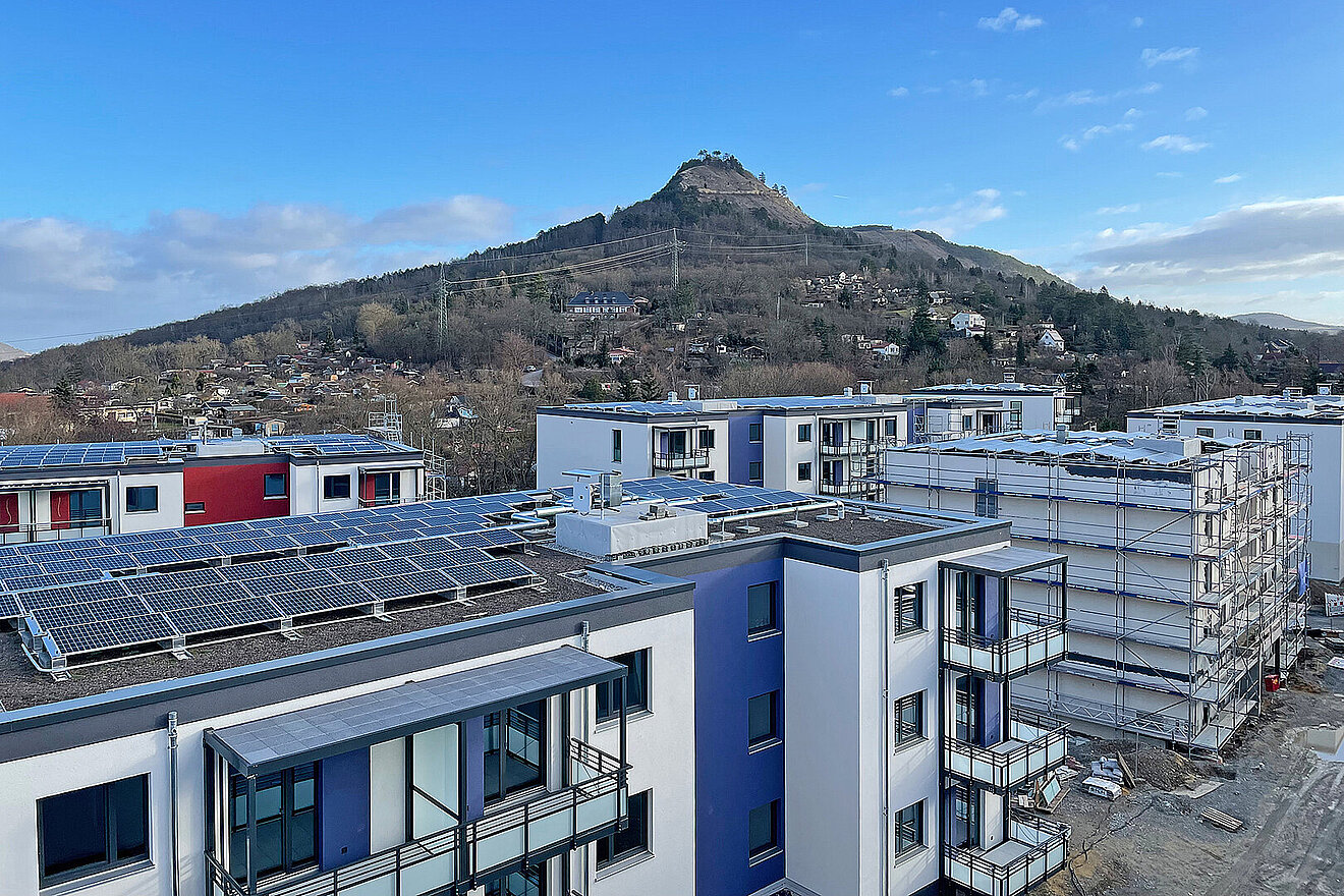 Blick über die Wohngebäude der Erlenhöfe in Jena-Ost mit Photovoltaikanlagen und dem Jenzig im Hintergrund.