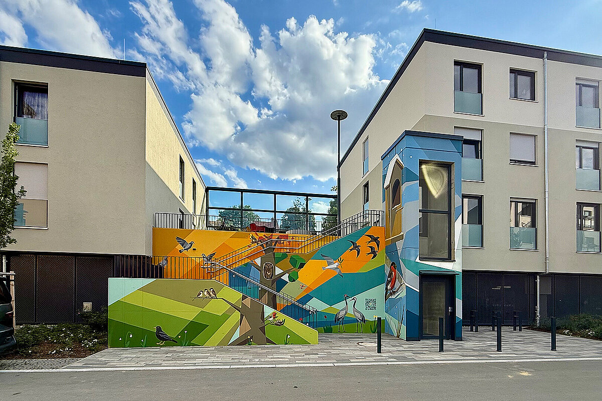 Innenhof der Erlenhöfe in Jena mit moderner Wohnbebauung, Treppenanlage und farbig gestalteter Fassadenkunst mit Tier- und Naturmotiven.